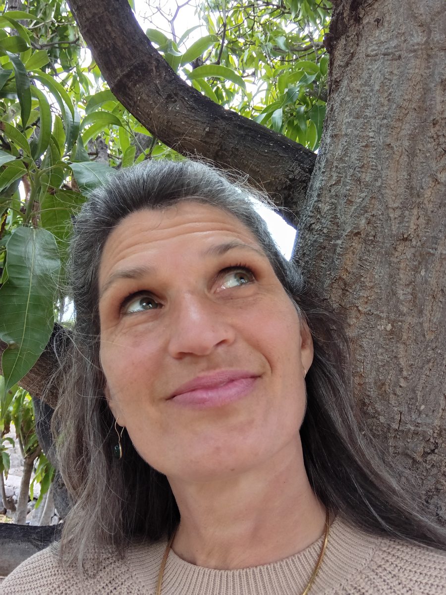 Antje Schmidt lächelt und blickt nach oben, im Hintergrund ein Baumstamm